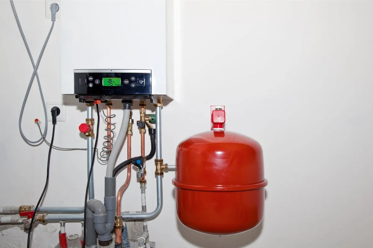 Cv-ketel aan de wand met leidingwerk en een rood expansievat